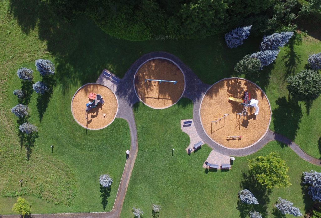 A small play area seen from directly overhead, set among grass and trees